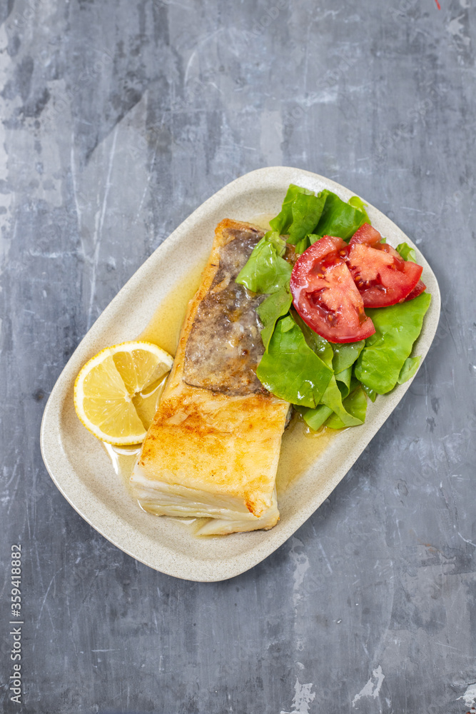 fried cod fish with fresh salad on dish on ceramic background fried cod fish with fresh salad on dish on ceramic background