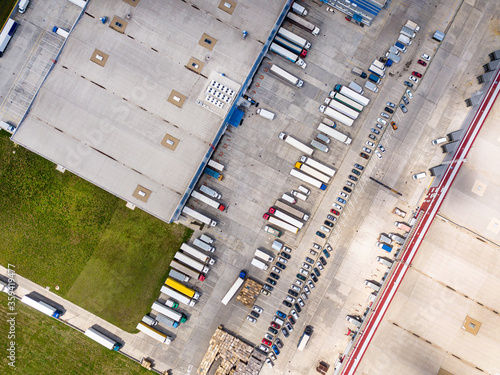 Aerial top view of the large logistics park with warehouse, loading hub with many semi-trailers trucks standing at the ramps for load unload goods.