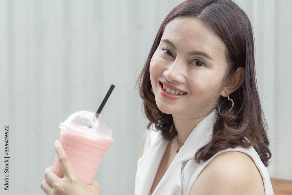 Closeup woman drinking strawberry smoothie and cake with green nature background, selective focus Closeup woman drinking strawberry smoothie and cake with green nature background, selective focus