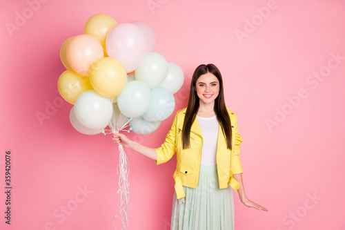Photo of funny charming lady long perfect hairdo hold many air balloons festive event birthday party wear trend yellow leather jacket green skirt isolated pastel pink color background