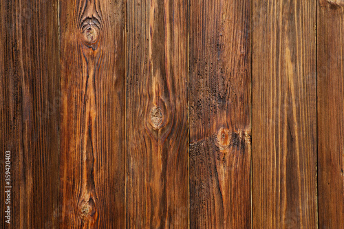 Wood texture. Brown dark boards with knots lie vertically.