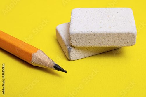 Valokuva Two erasers and pencil on yellow background