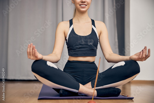 Slim young female smiling while doing yoga