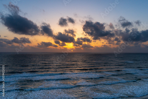 Beautiful sunset with dark blue sky and orange golden colors sun over the sea with dramatic clouds in the sky and waves close to the beach shore concept of romantic time on vacation