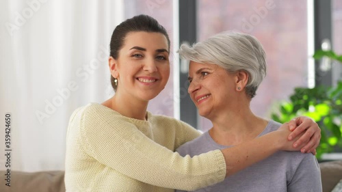 family, generation and people concept - happy smiling senior mother with adult daughter hugging at home photo