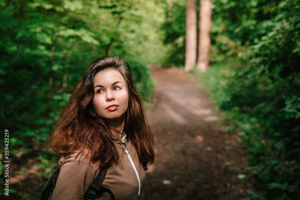 A young girl with long hair walks in the woods. Hiking with tents or traveling to natural places A young girl with long hair walks in the woods. Hiking with tents or traveling to natural places