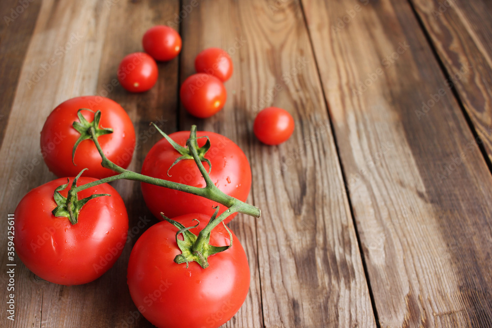 Fresh tomatoes on the vine and cherry tomatoes on rustic wooden table Fresh tomatoes on the vine and cherry tomatoes on rustic wooden table