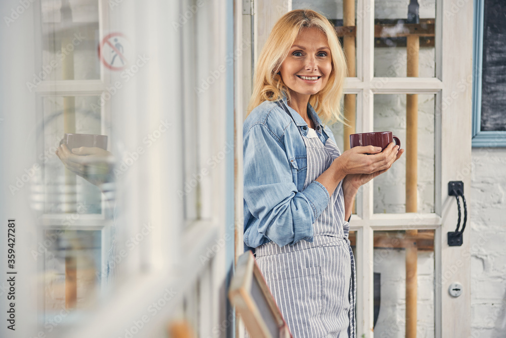 Joyful lady with a mug of coffee standing outdoors Joyful lady with a mug of coffee standing outdoors