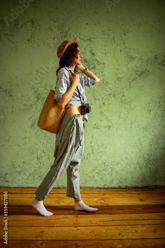 Tourist in a denim jacket and hat with a camera and bag. Happy emotions