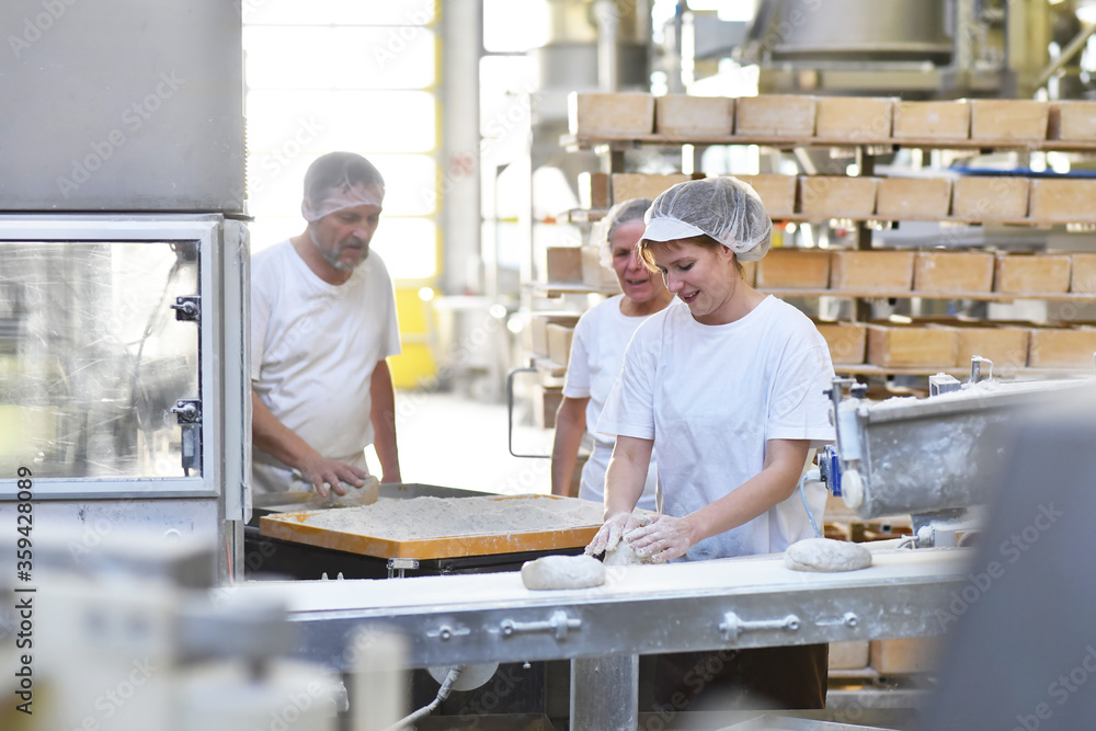Worker in a large bakery - industrial production of bakery products on an assembly line Worker in a large bakery - industrial production of bakery products on an assembly line