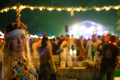 woman in yellow santa claus hat smiling, in the background festive lights of new year