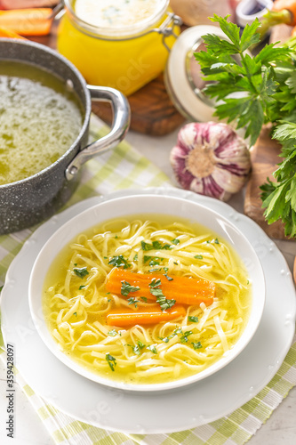 Chicken soup broth in a plate carrot onion celery herbs garlic and fresh vegetables