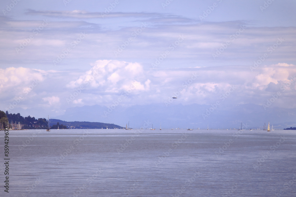 Zeppelin aircraft fly over the Lake of Constance. Landscape of Bodensee lake with some small boats on the horizon