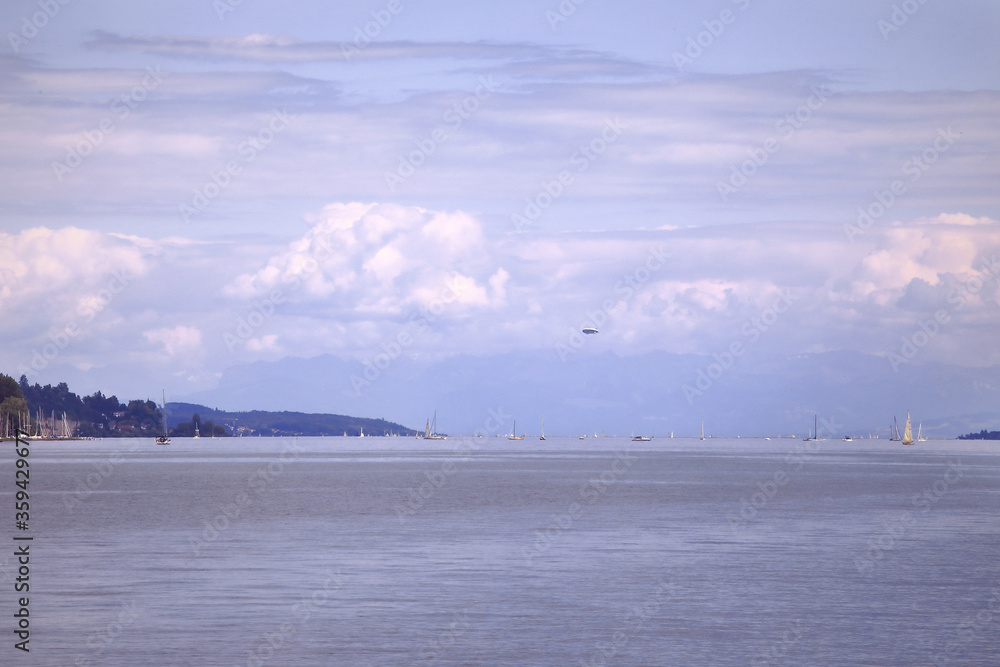 Zeppelin aircraft fly over the Lake of Constance. Landscape of Bodensee lake with some small boats on the horizon
