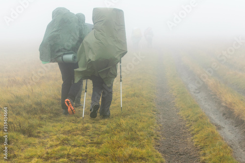 A group of hikers walk in the fog.