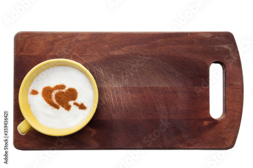 Top view of a cup of coffee with cream decorated. Food art creative concept image, drawing with cinnamon powder over wooden background.