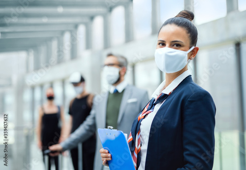 Portrait of flight attendant standing on airport, wearing face masks. photo