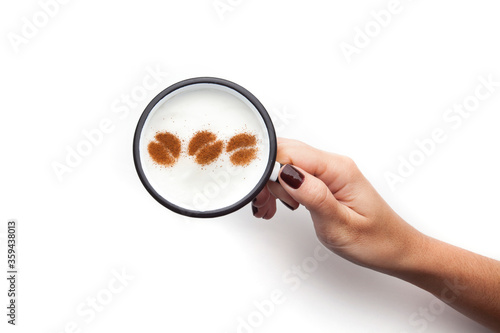 A retro cup with coffee cream. Food art creative concept image, cute drawing with cinnamon powder over milk cream on a white background.