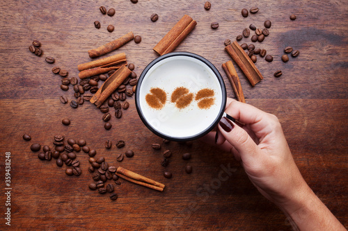 A retro cup with coffee cream. Food art creative concept image, cute drawing with cinnamon powder over milk cream on a wooden background.