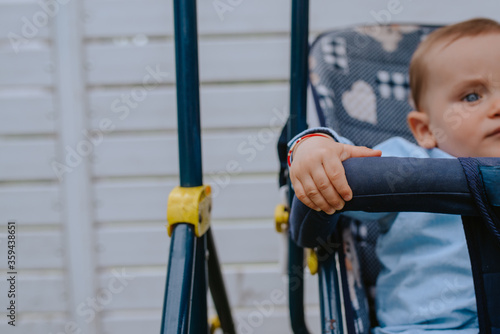 A beautiful caucasian child in a stroller in the yard
