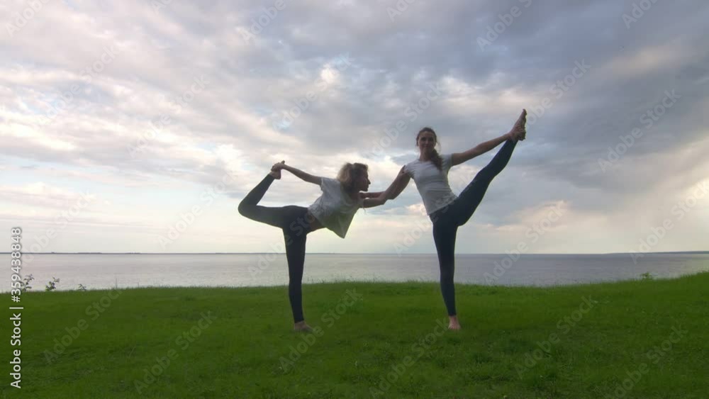 Two women in activewear posing on the camera and showing together yoga Lord of the Dance pose and Standing Hand to Toe Two women in activewear posing on the camera and showing together yoga Lord of the Dance pose and Standing Hand to Toe