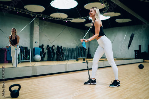 Cheerful female exercising with rubber band in gym