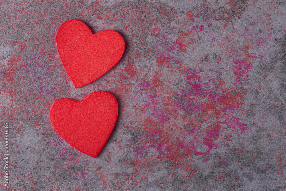 Obraz premium Two red hearts on color stone background with copy space