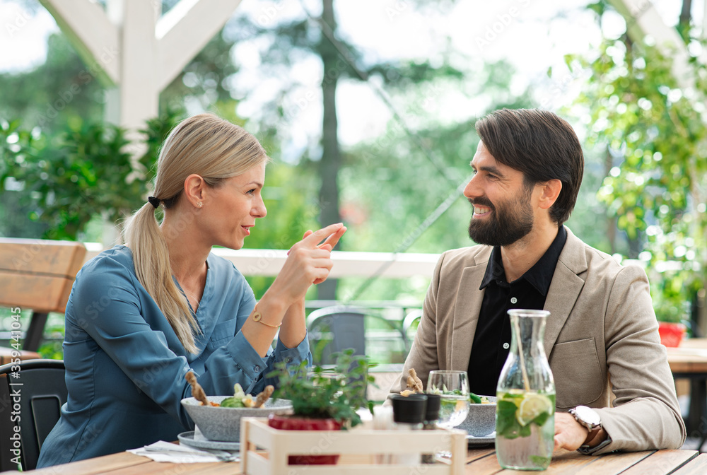 Happy couple sitting outdoors on terrace restaurant, talking. Happy couple sitting outdoors on terrace restaurant, talking.