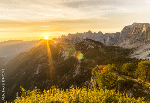 Amazing sunrise in the mountains. Backlight Sunlight with beautiful lens flares and sunbeams. Julian Alps, Triglav National Park, Slovenia, Mountain Slemenova, Sleme. photo