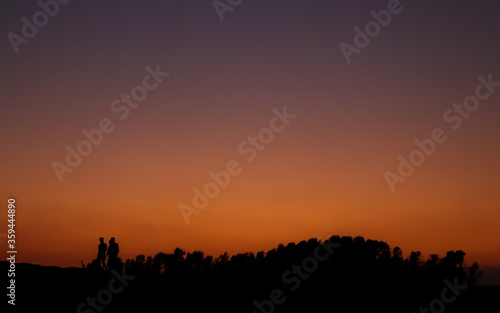 People walking under the orange sky after sunset