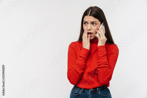 Photo of scared woman expressing shock while talking on mobile phone