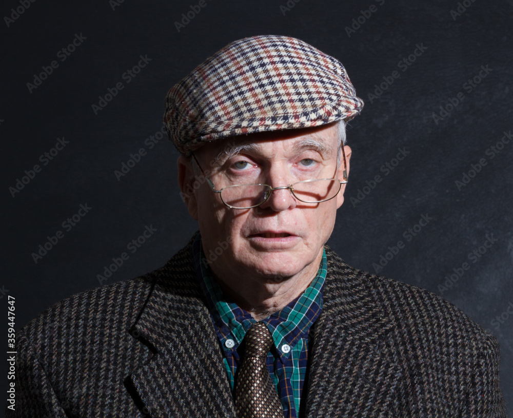 Older man in flat cap peering over halfmoon glasses whole looking very drunk Older man in flat cap peering over halfmoon glasses whole looking very drunk