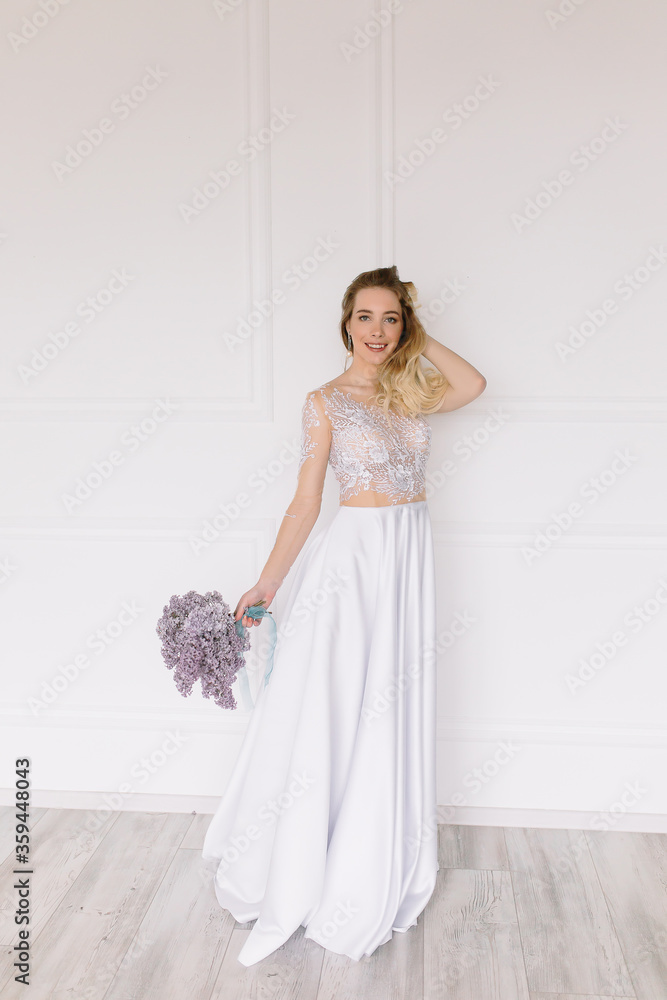 Beautiful girl woman bride in a delightful wedding dress with a bouquet of flowers dancing in front of a mirror portrait of a blonde with blue eyes holding Beautiful girl woman bride in a delightful wedding dress with a bouquet of flowers dancing in front of a mirror portrait of a blonde with blue eyes holding