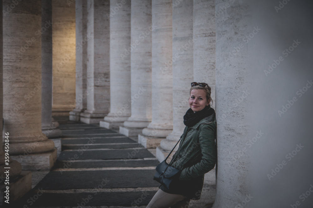 Tourist girl between ancient columns in Vatican square Rome