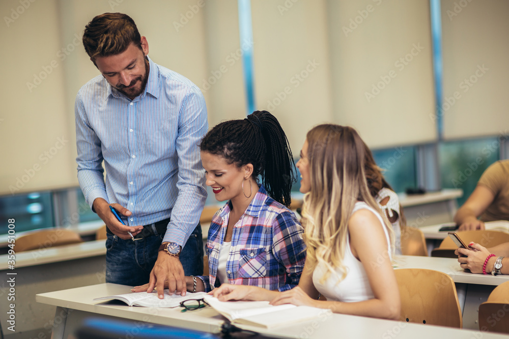 Group of smiling students and teacher with notebook in classroom Group of smiling students and teacher with notebook in classroom