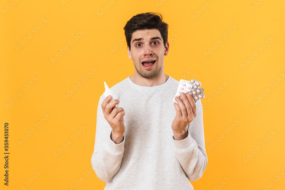 Photo of unhappy man with allergy posing with pills and nose drop Photo of unhappy man with allergy posing with pills and nose drop
