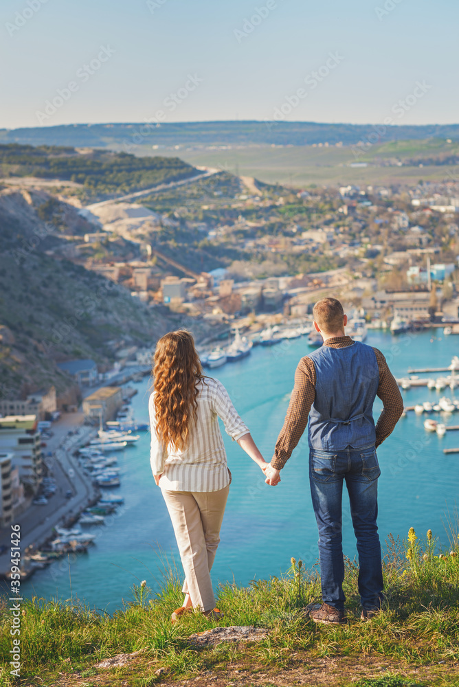 Young couple in love outdoor.Stunning sensual outdoor portrait of young stylish fashion couple posing on the background of mountains and sea Young couple in love outdoor.Stunning sensual outdoor portrait of young stylish fashion couple posing on the background of mountains and sea