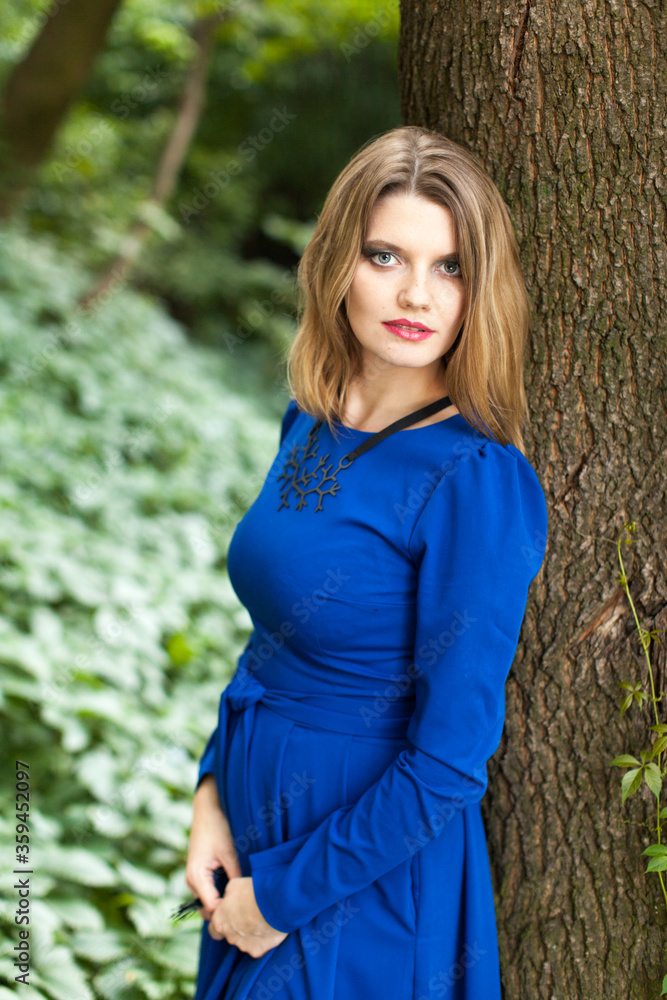 Beautiful blonde woman with make up in blue dress in the forest Beautiful blonde woman with make up in blue dress in the forest