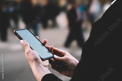 Cropped view of woman's hands holding modern smartphone with mock up area and installing app using 4G internet connection.Updating profile on digital telephone device.Selective focus on mobile phone