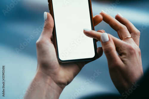 Cropped view of young woman's hands holding digital smartphone and typing with finger text message on blank display of device using high speed 4G internet connection for online chat © BullRun
