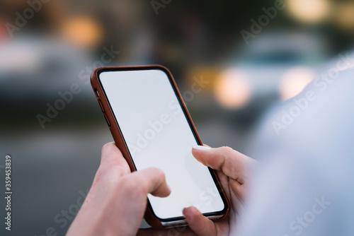 Cropped view of woman's hands holding smartphone with blank screen area for your internet content on website.Selective focus on female fingers typing text message on telephone with mock up area