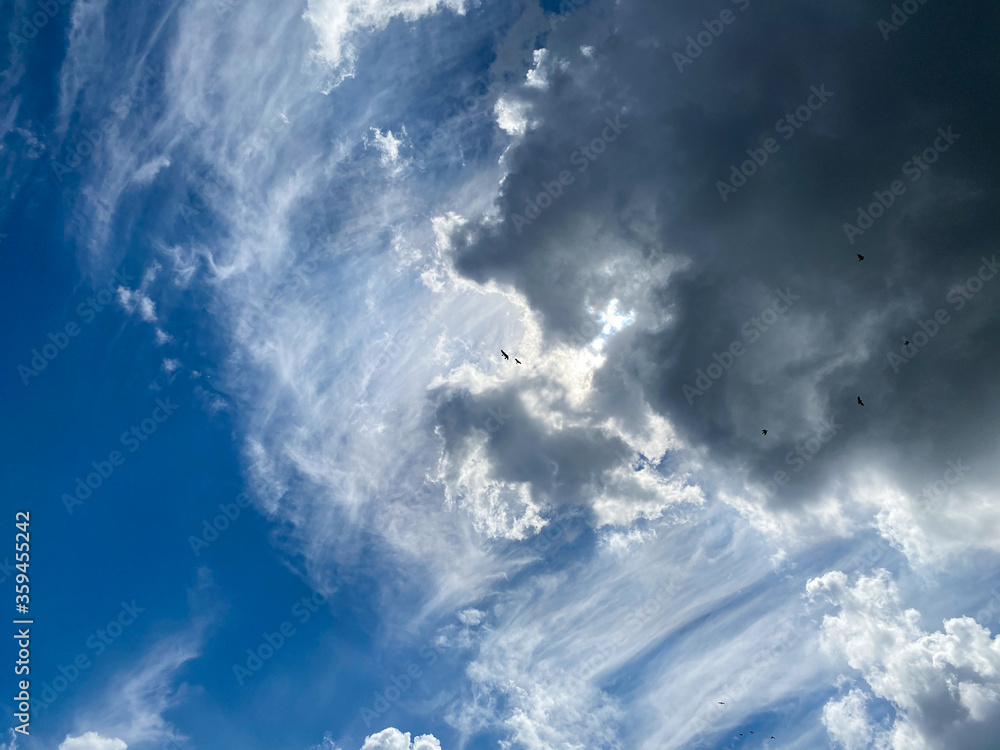 Obraz premium View into deep blue sky with stratocumulus and cirrus clouds on windy day announcing occasional summer rain showers