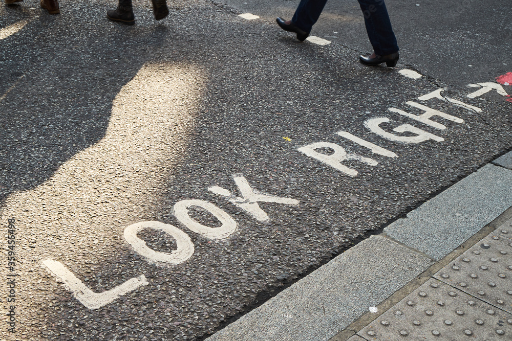custom made wallpaper toronto digitalWhite look right warning sign in writing on the asphalt with feet of pedestrians crossing at sunset in London.