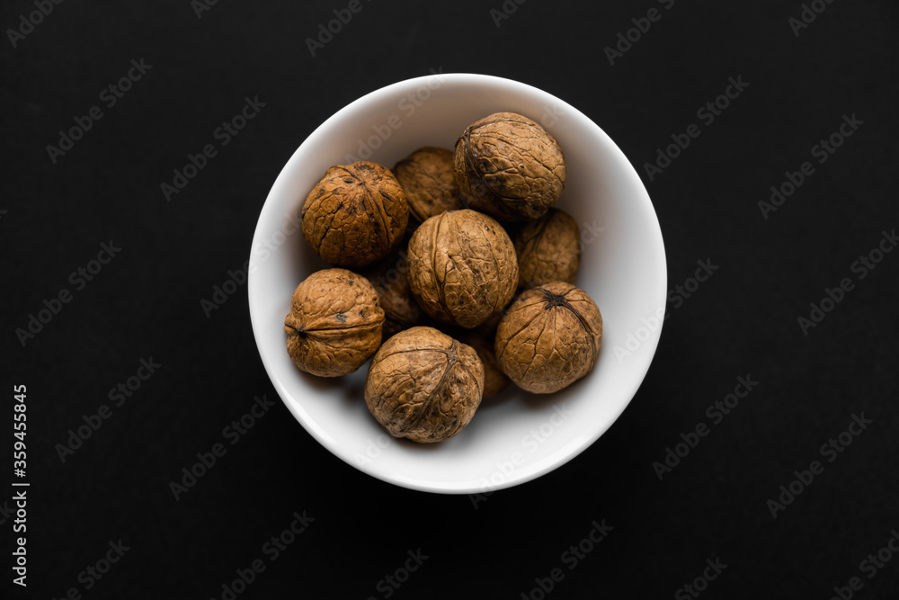 Walnut in a small plate on a black table. Walnuts is a healthy vegetarian protein nutritious food. Natural nuts snacks. Walnut in a small plate on a black table. Walnuts is a healthy vegetarian protein nutritious food. Natural nuts snacks.