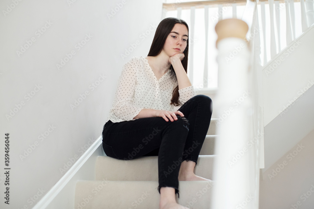 Fed Up Teenage Girl Sitting On Stairs At Home Fed Up Teenage Girl Sitting On Stairs At Home