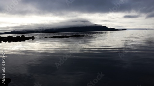 Stunning Mysterious moody, cloudy, misty, Ketchikan Alaska mountain with calm seas in the foreground.