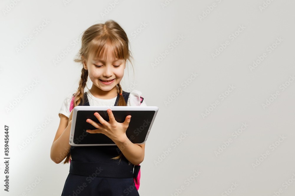 The little girl using the tablet on the white wall background The little girl using the tablet on the white wall background