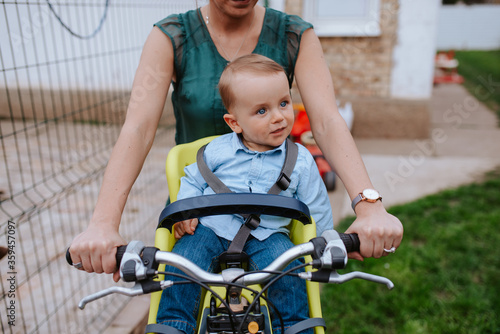 A caucasian mother rides a beautiful child on a bicycle