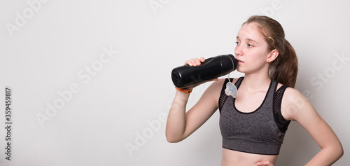 Young beautiful sporty girl doing sport wearing sportswear. Cute girl drinks water from a bottle. © Eugene