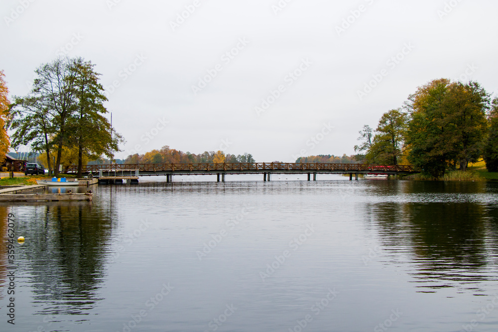 Bridge in Galve lake in Trakai, Lithuania. Autumn trees. Bridge in Galve lake in Trakai, Lithuania. Autumn trees.